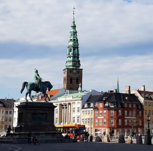 Statue af Kong Frederik 7. foran Christiansborg Slot, set fra slottet med gaden og byen i baggrunden